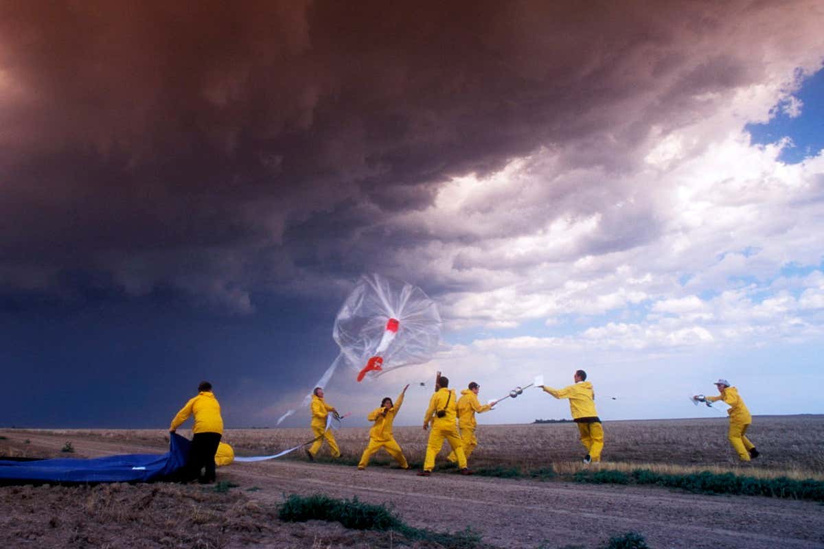 Storm research. Meteorologists from the Severe Thunderstorm Electrification and Precipitation Study (STEPS) prepare to launch a weather balloon into a storm. This is a tornadic supercell thunderstorm, a massive thunderstorm that is in the process of developing a tornado. The weather balloon carries instruments that will obtain data on temperature, pressure, wind speed and electrical fields within the thunderstorm itself. Photographed in Kansas, USA.