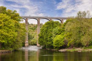 Pontcysyllte Aqueduct, built by Thomas Telford, and a World Heritage Site, reflecting in the River Dee, with people walking across, near Llangollen, County Borough of Wrexham, Wales, UK