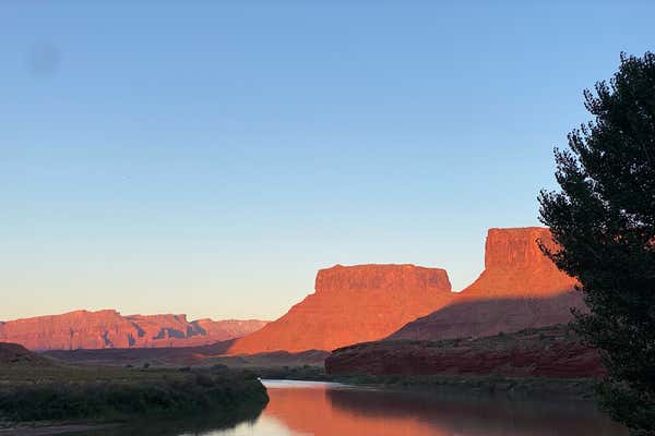 View of Colorado river traversing through landscapes at sunset casting a beautiful red light on the surrounding peaks